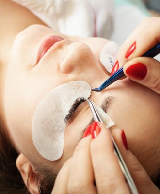 Eyelash extensions in a beauty salon. A young girl lies on a couch